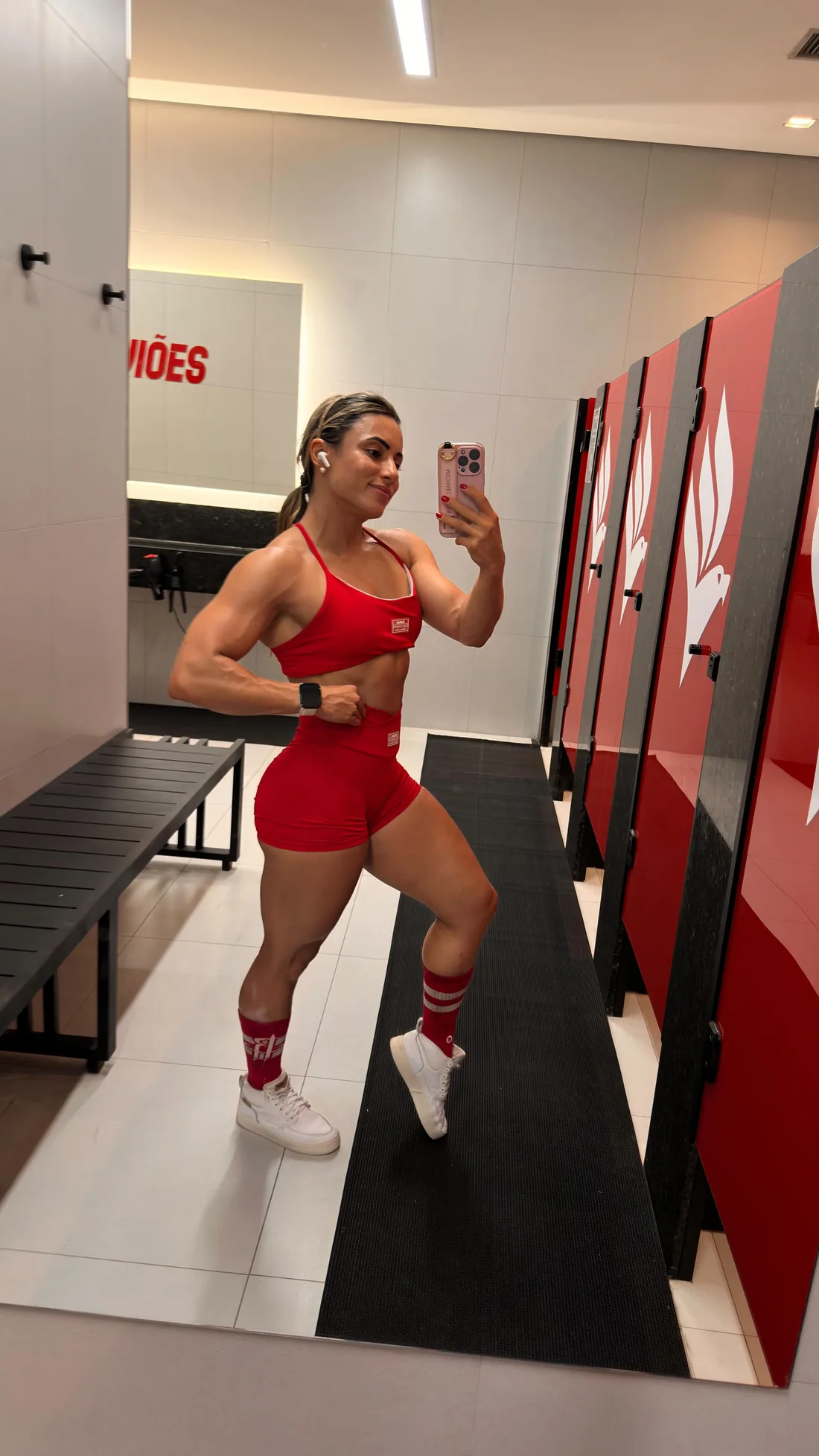 Monique Ribeiro de conjunto vermelho no vestiário da Gaviões, com armários vermelhos ao fundo